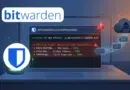Laptop displaying a compromised Bitwarden CLI with a red alert, shield icon, and a hacker in a cloud in the background.