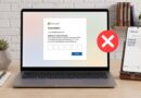 Laptop shows a fake Microsoft sign-in with a security code entry and a red X, indicating a blocked login; a phone on a stand displays a code SMS beside it.