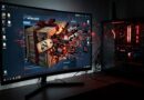 Gaming setup with a curved monitor showing a Steam Workshop splash and a crate exploding on screen, plus a red-lit PC tower to the right