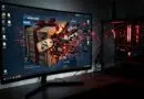 Gaming setup with a curved monitor showing a Steam Workshop splash and a crate exploding on screen, plus a red-lit PC tower to the right
