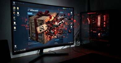 Gaming setup with a curved monitor showing a Steam Workshop splash and a crate exploding on screen, plus a red-lit PC tower to the right