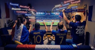 Group of France 2026 soccer fans in a living room, wearing blue jerseys and waving scarves as they cheer a match on the TV.