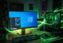 Gaming desktop setup with a monitor, keyboard, mouse, and a PC case emitting bright green LED glow.