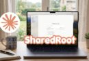 Laptop on a wooden desk displaying software UI with ShareDRoot branding; a mug, notebook, and small plant nearby.