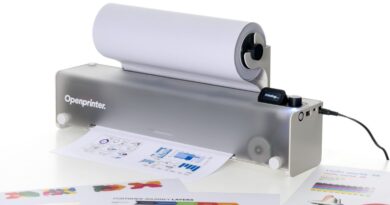 Openprinter desktop printer with a roll of paper feeding through, printing sheets in front of it