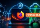Laptop shows Firefox logo with a prominent Firefox 154 badge, surrounded by cloud and shield/security icons, plus a gaming controller in the foreground.