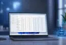 Laptop on a desk showing a data-management dashboard on screen, with a blue holographic NPU graphic and chart nearby.