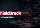 ShieldBreak banner over a hacker's dark workstation showing 'Zero-Day Windows' exploit text on a laptop screen in a data-center setting.